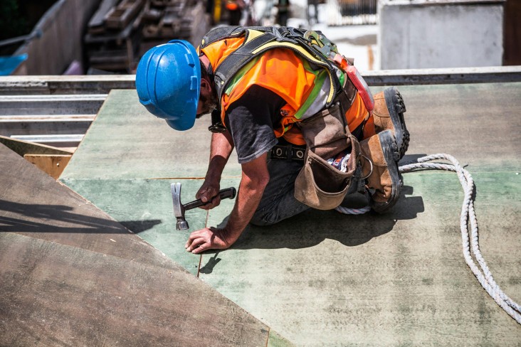 Construction worker hammering material in place